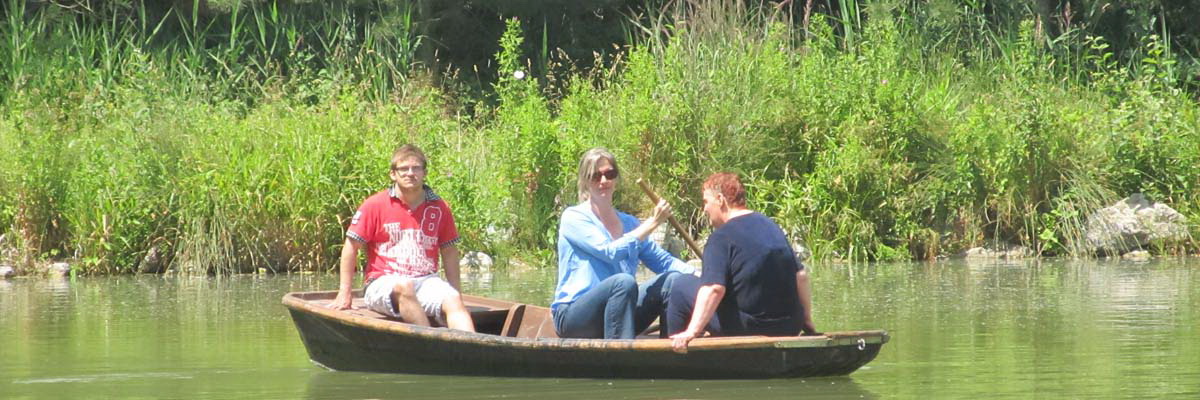 Drei Personen in einem kleinen Ruderboot